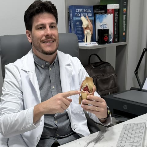 Dr. Rúbio Arruda na mesa do consultório explicando com o modelo anatômico do joelho